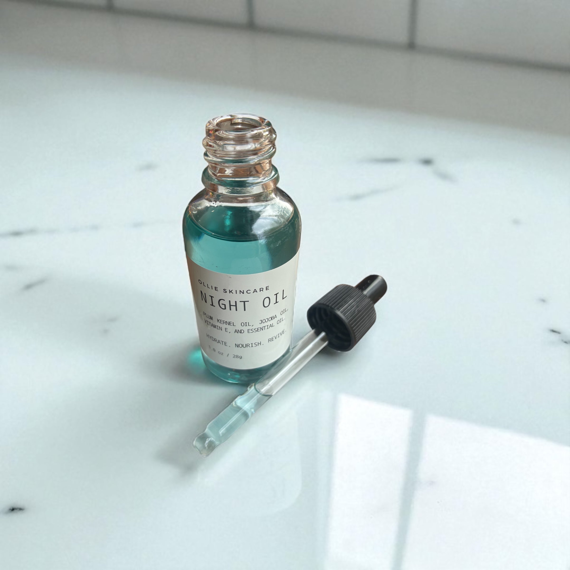 Bottle of night oil with a dropper on a marble surface