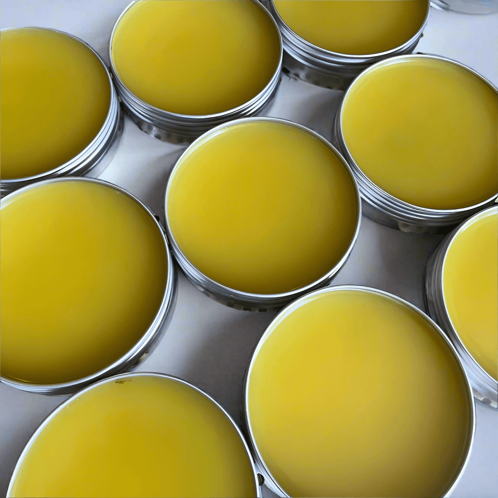 Handcrafted Muscle Rub in silver tins, showcasing its yellow, soothing formula for tired muscles and joints.