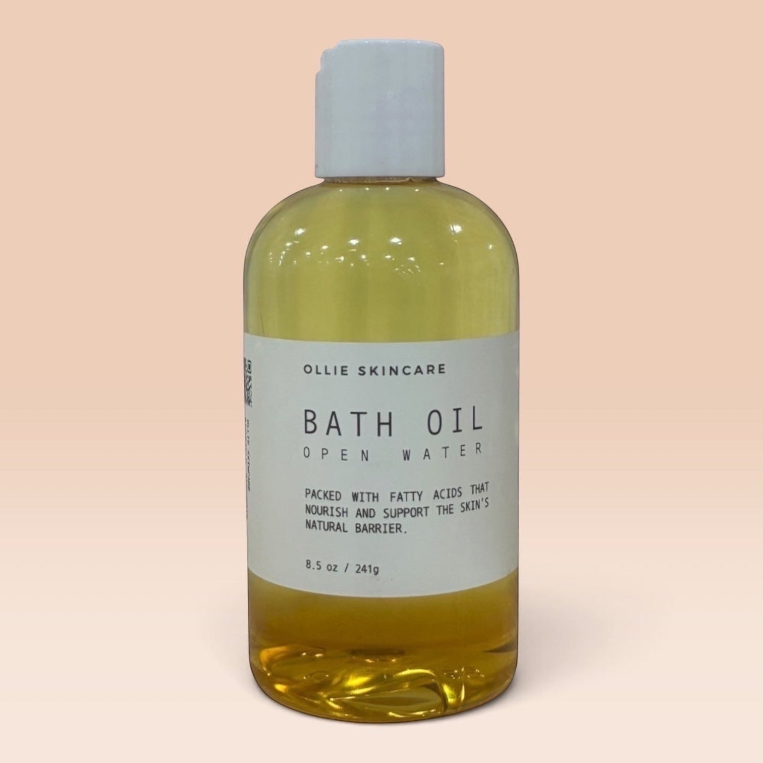 Ollie Skincare bath oil in a clear bottle with a white cap, formulated for deep skin hydration.