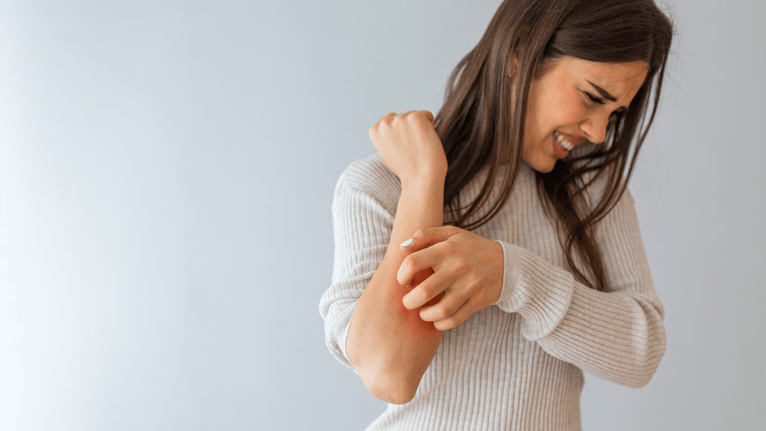 Woman experiencing skin discomfort as she cares for her sensitive skin.