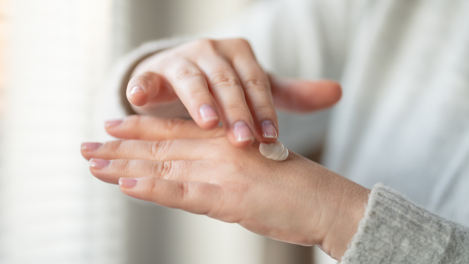Hands applying body lotion