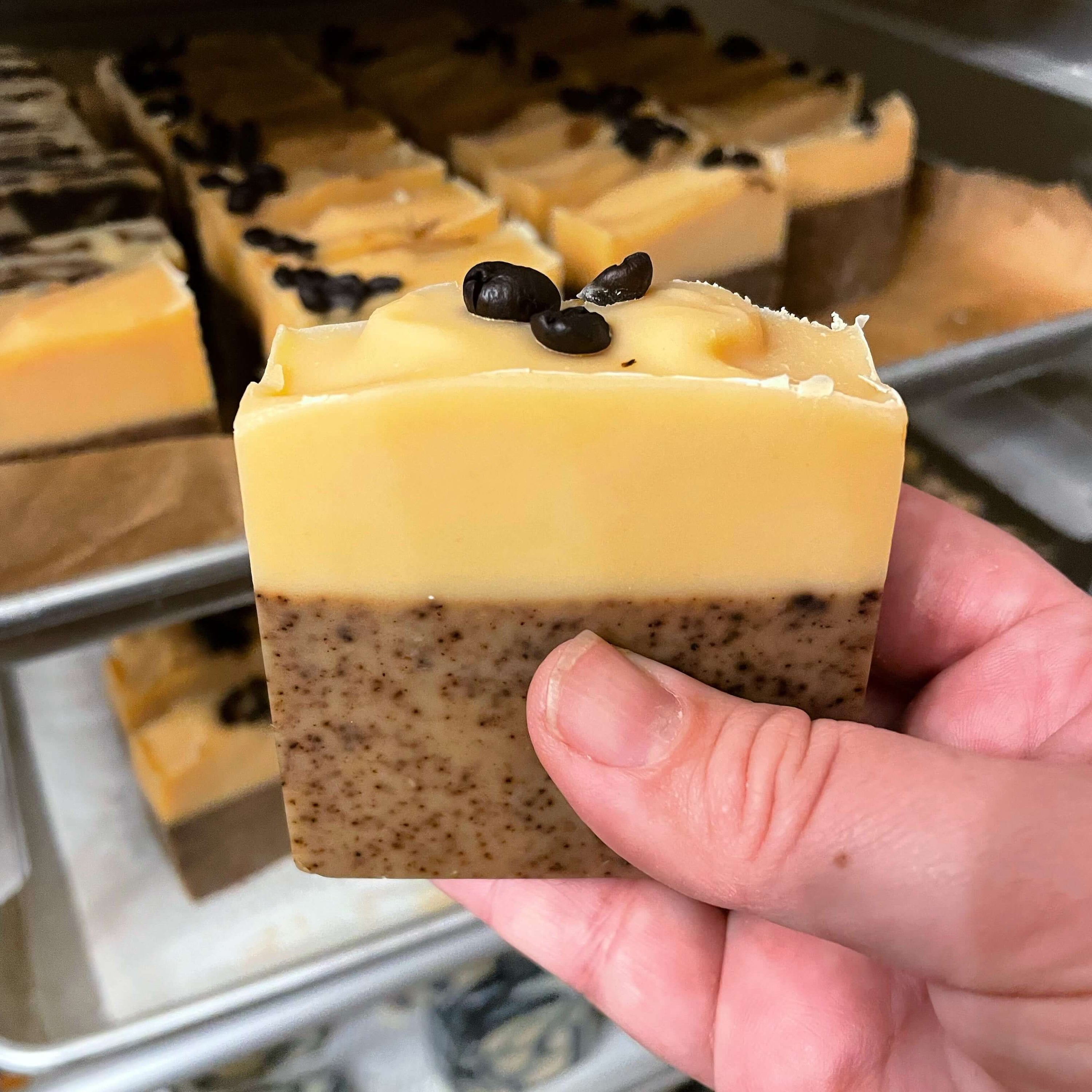 Discover the surprising benefits of goat milk soap with a hand holding a bar featuring coffee beans.