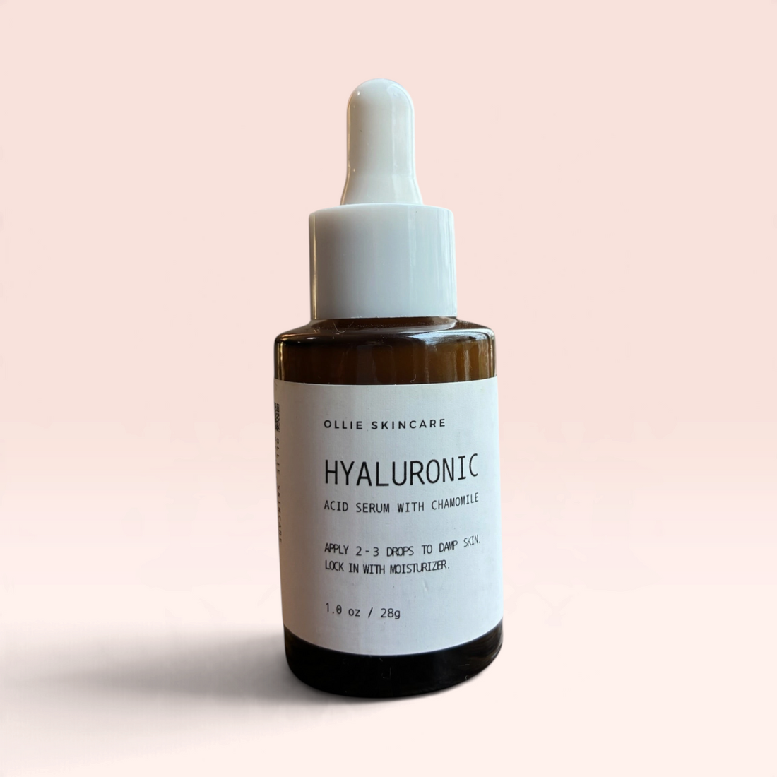 OLLIE SKINCARE Hyaluronic Acid Serum in a brown glass dropper bottle with a white label against a soft pink background
