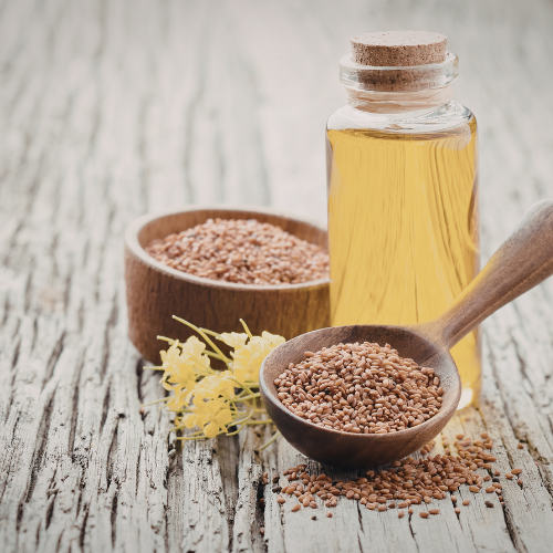 Bottle of oil with wooden spoon and bowl of seeds on a rustic wooden surface