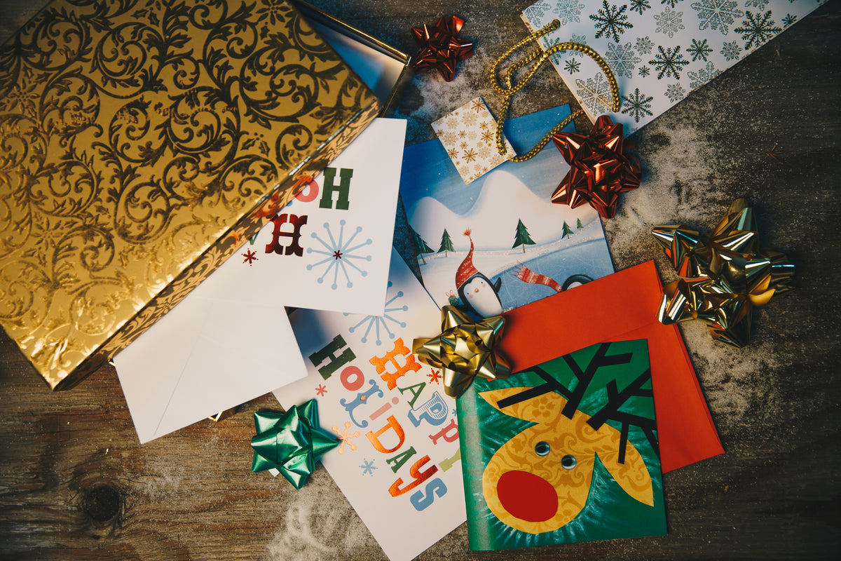 Holiday cards, gold wrapping paper and gift bows on a wooden table