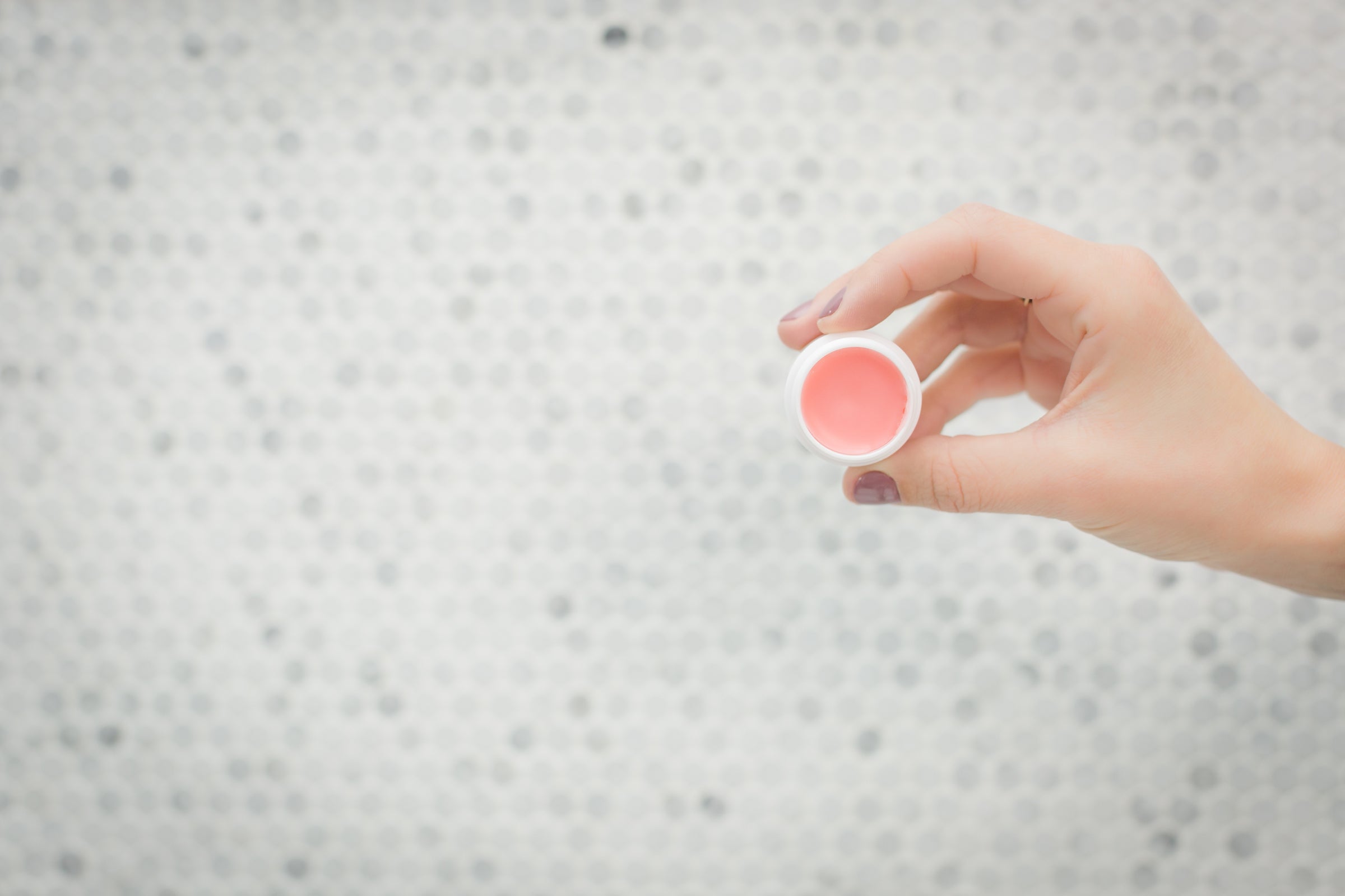 Lip balm in white containter held in hand