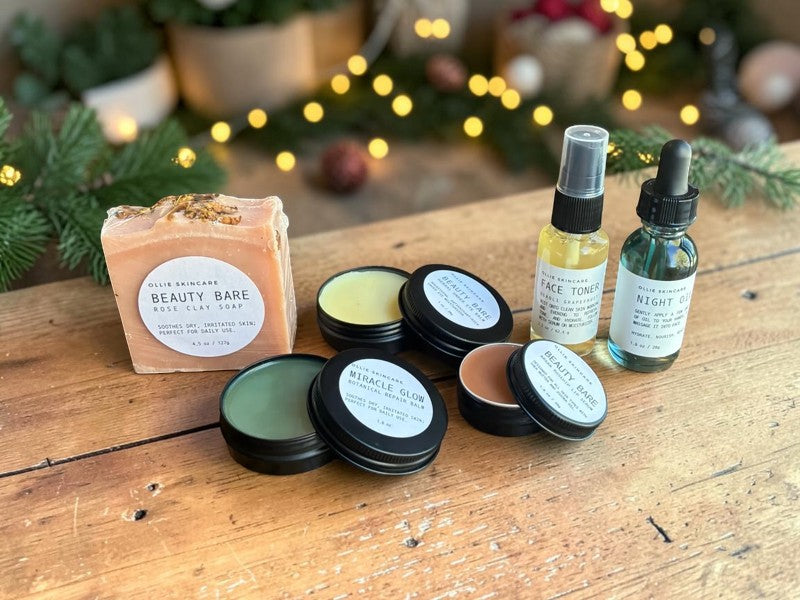 Glow Ritual gift set: rose clay soap, open balm tins, face toner mist and night oil with holiday lights behind.