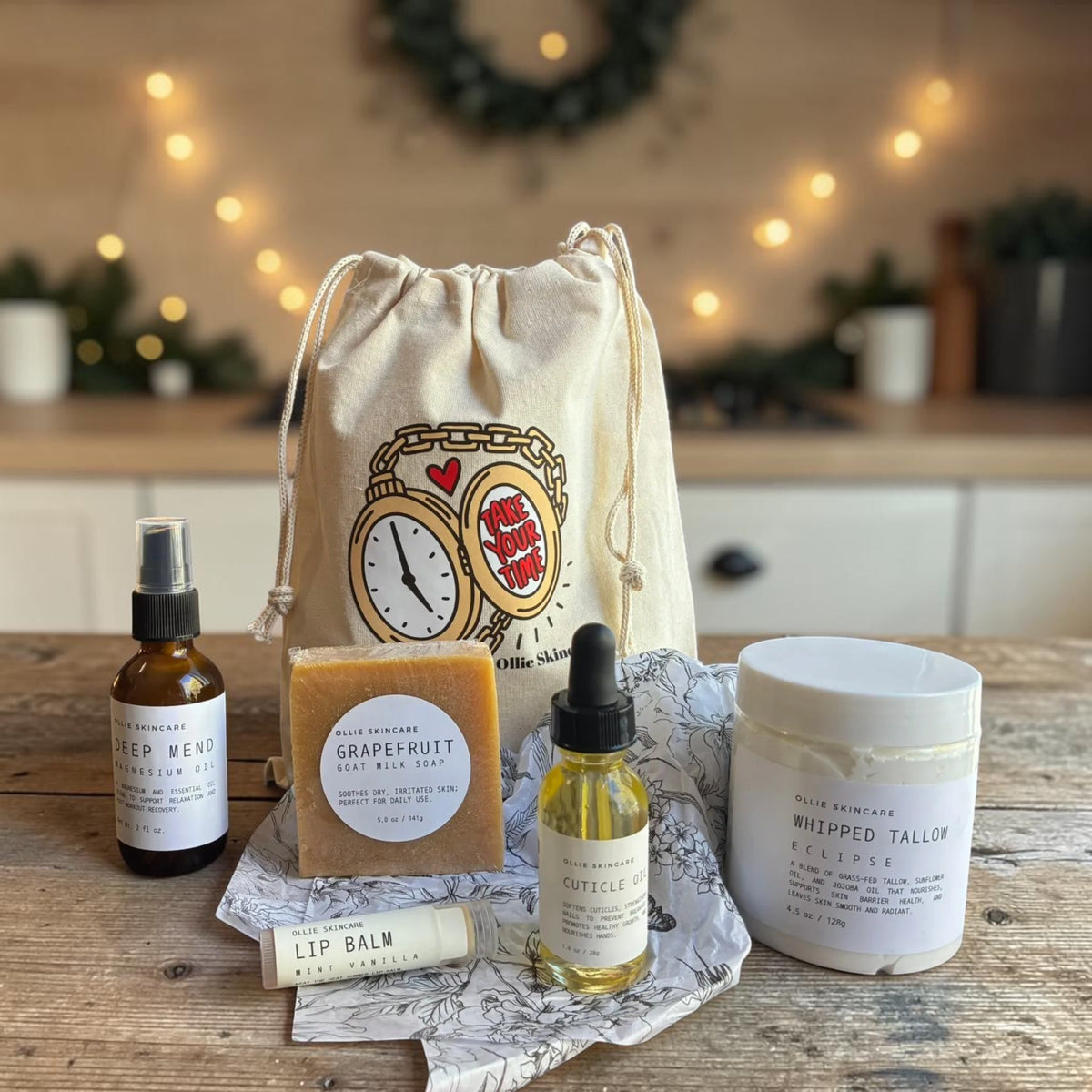 Winter Skin Rescue gift set in front of its cotton gift bag: magnesium oil, Grapefruit goat milk soap, cuticle oil, Whipped Tallow and lip balm.