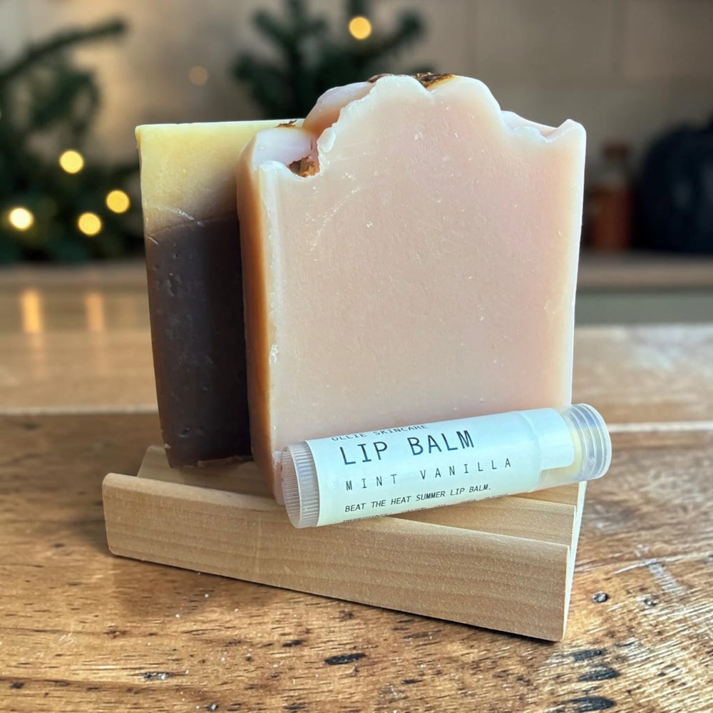 The Soap Lover gift set: two goat milk soap bars on a wooden soap tray with a lip balm, beside a 'Take a Moment' cotton gift bag.