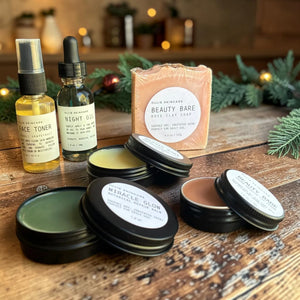 Close-up of the Glow Ritual gift set's open balm tins with the face toner mist, night oil and rose clay soap behind them.