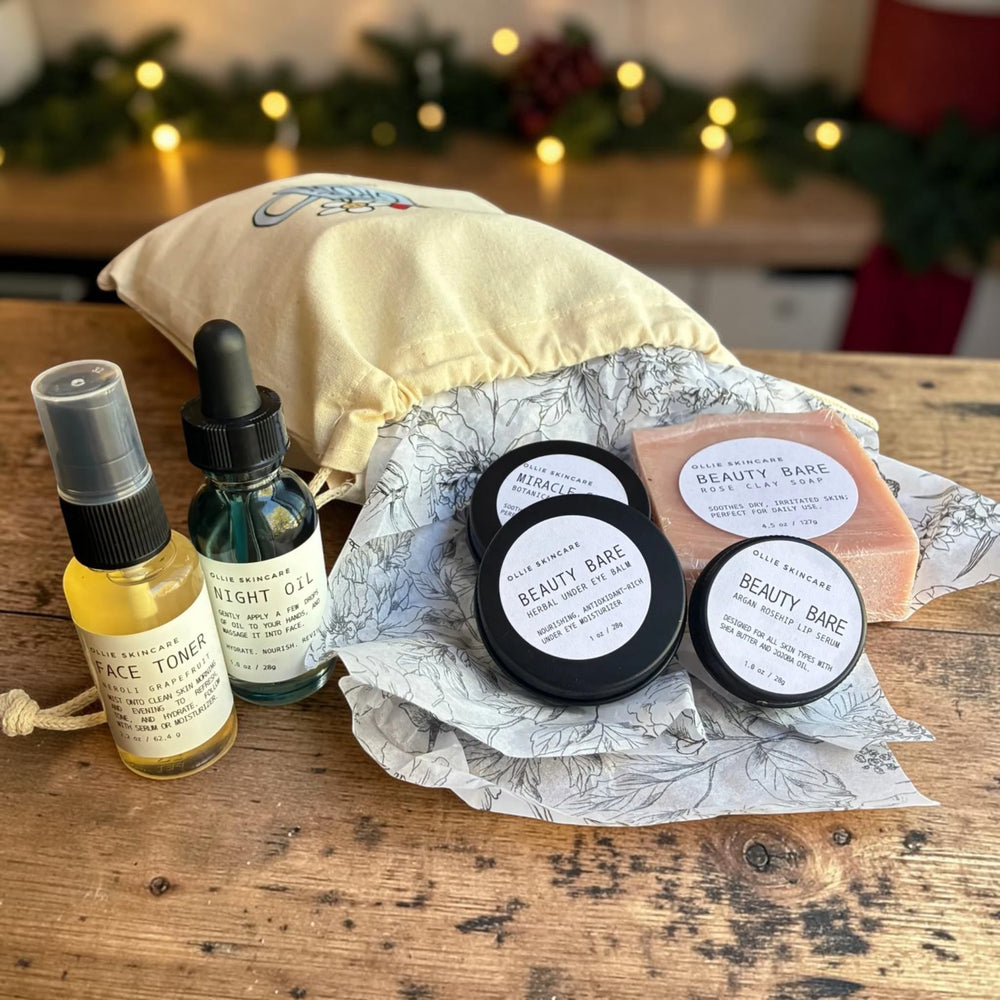 The Glow Ritual gift set: face toner mist, night oil, three balm tins and rose clay facial soap spilling from a cotton gift bag.