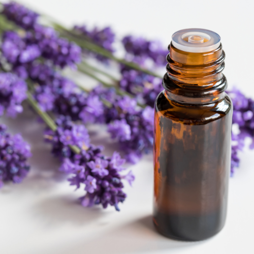 Brown glass essential oil bottle with lavender flowers on a light background