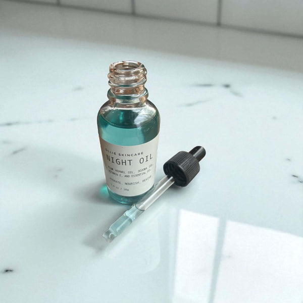 Night Facial Oil in a glass dropper bottle on a marble surface with a dropper top.