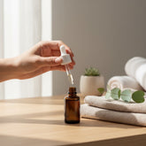 OLLIE SKINCARE Bakuchiol Facial Oil in an amber glass dropper bottle being applied on a wooden table with towels.