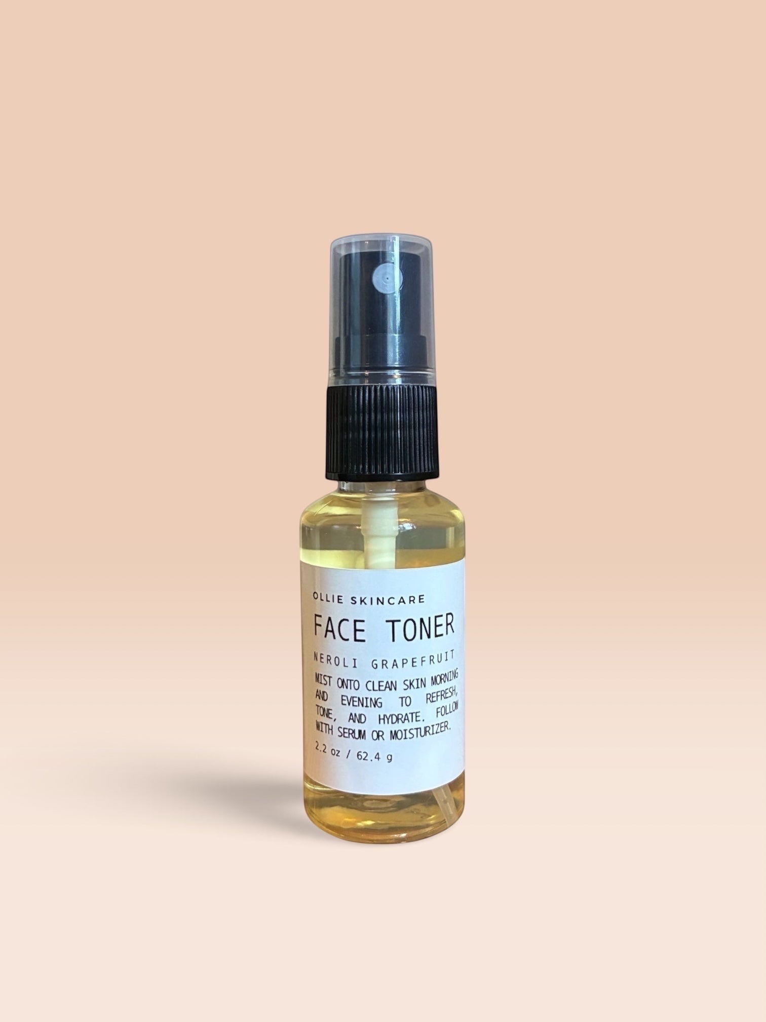 OLLIE SKINCARE Neroli Grapefruit Face Toner Mist in a clear spray bottle with a black cap against a peach background.