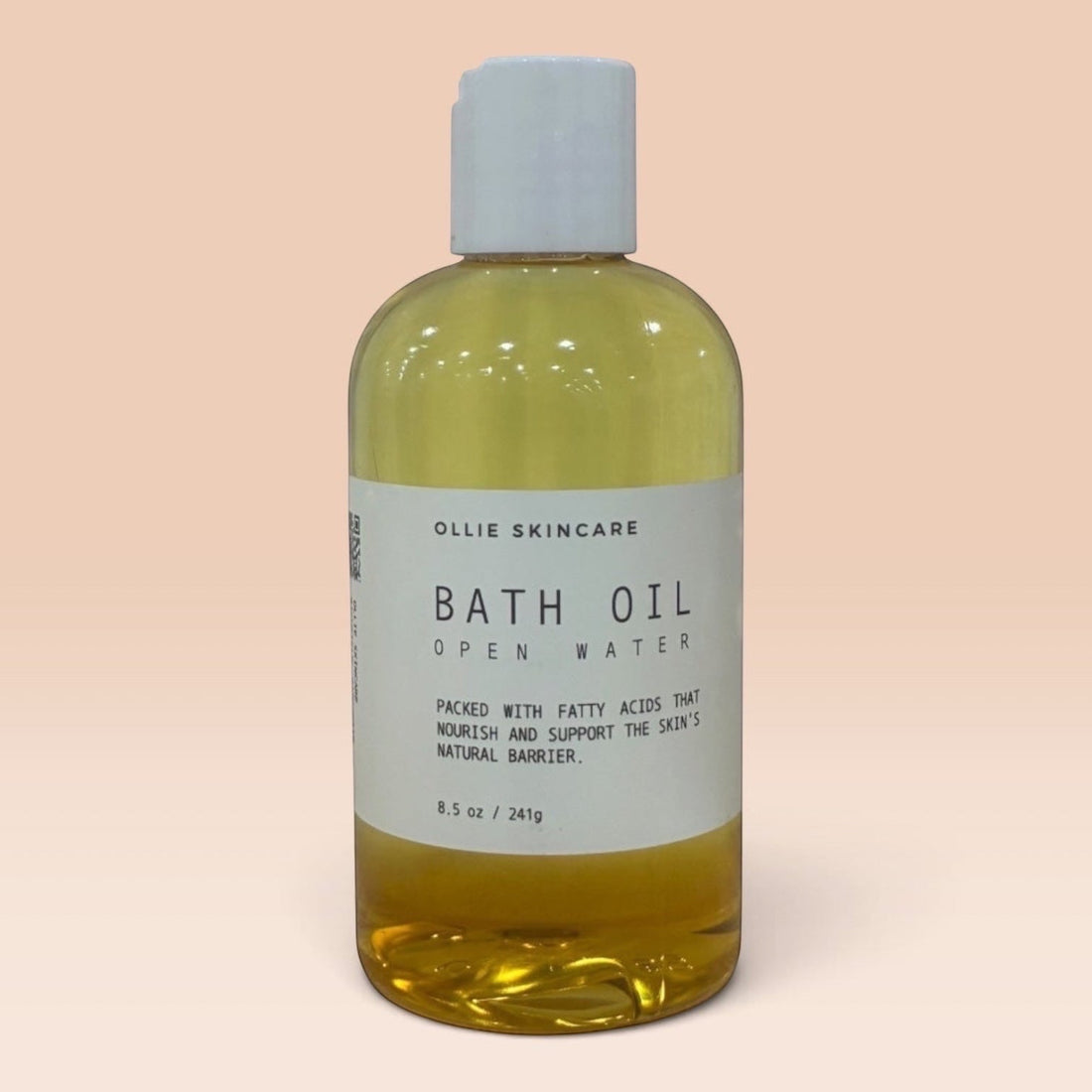 Ollie Skincare bath oil in a clear bottle with a white cap, formulated for deep skin hydration.