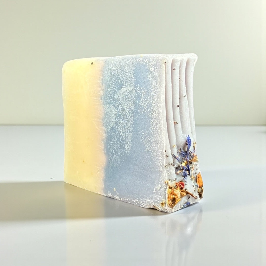 Rainy Day Goat Milk Soap bar featuring soft blue and yellow colors with floral decorations.
