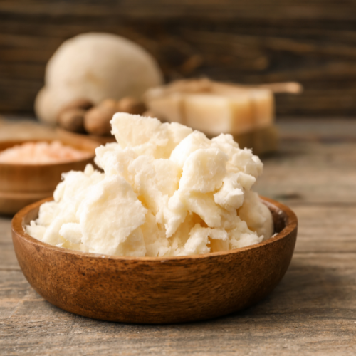 Wooden bowl filled with shea butter on a wooden surface