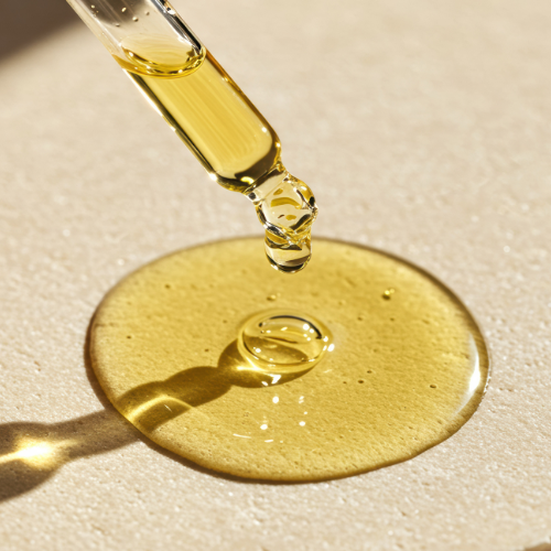 Yellow liquid being dripped from a dropper onto a beige surface.
