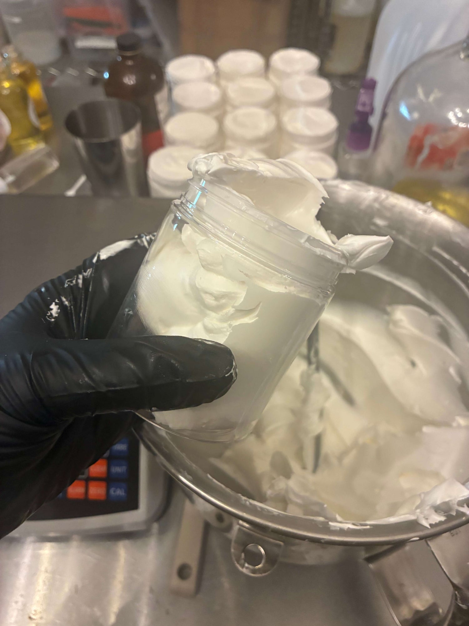 Jar of whipped tallow skincare product being held above a mixing bowl of whipped tallow.