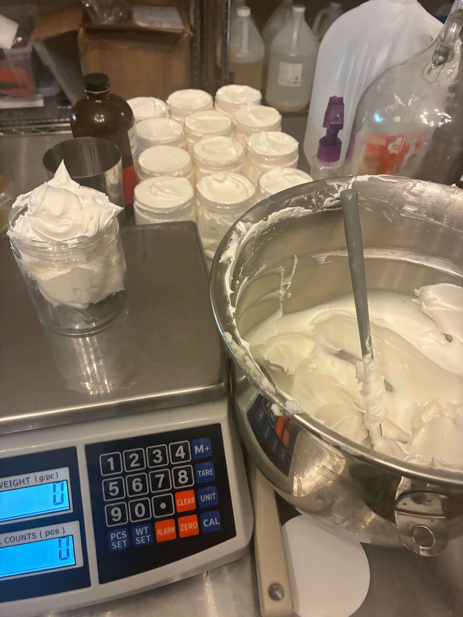Whipped Tallow in mixing bowl alongside filled jars ready for skincare application, showcasing luxury skincare making process.