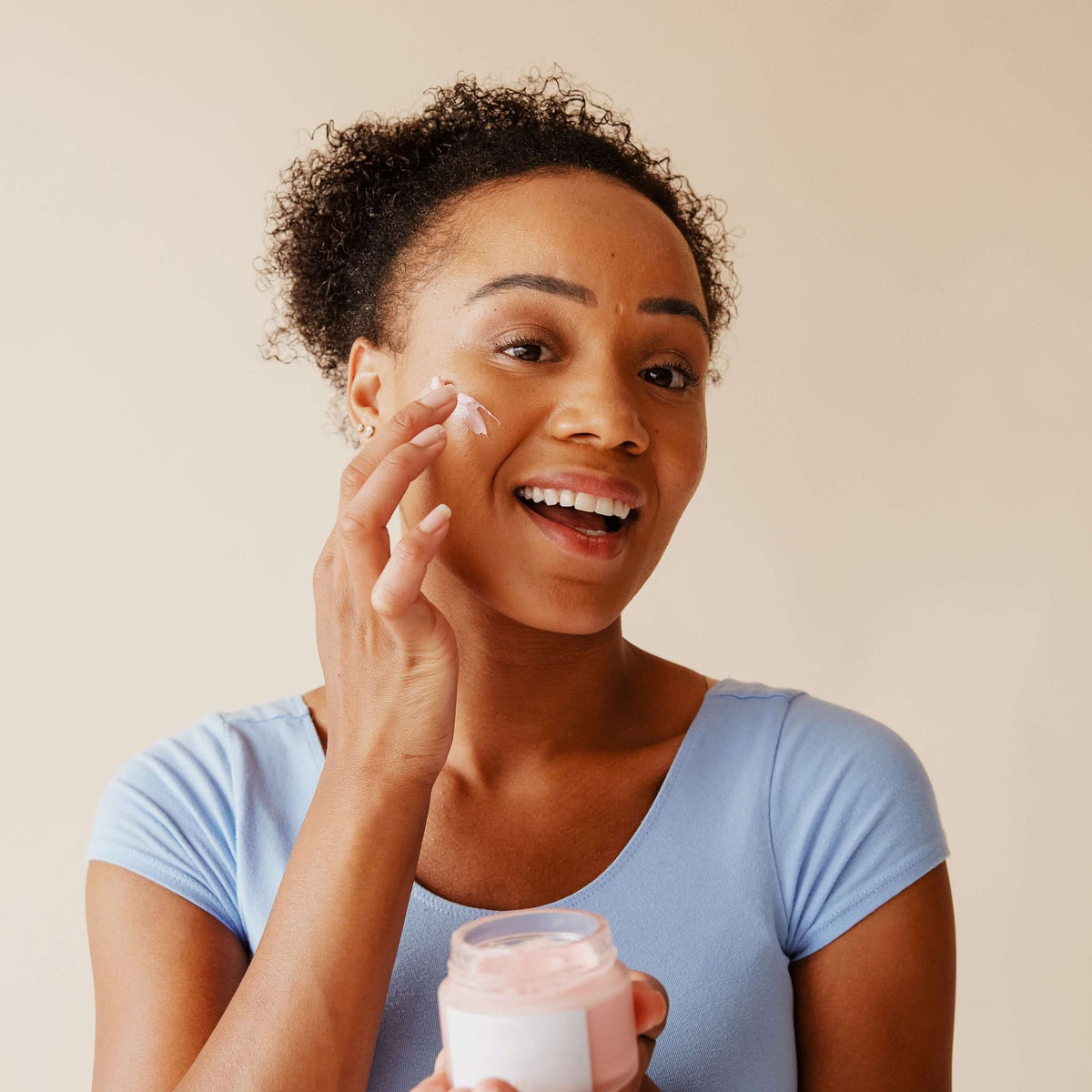 Woman applying skincare in her bathroom mirror