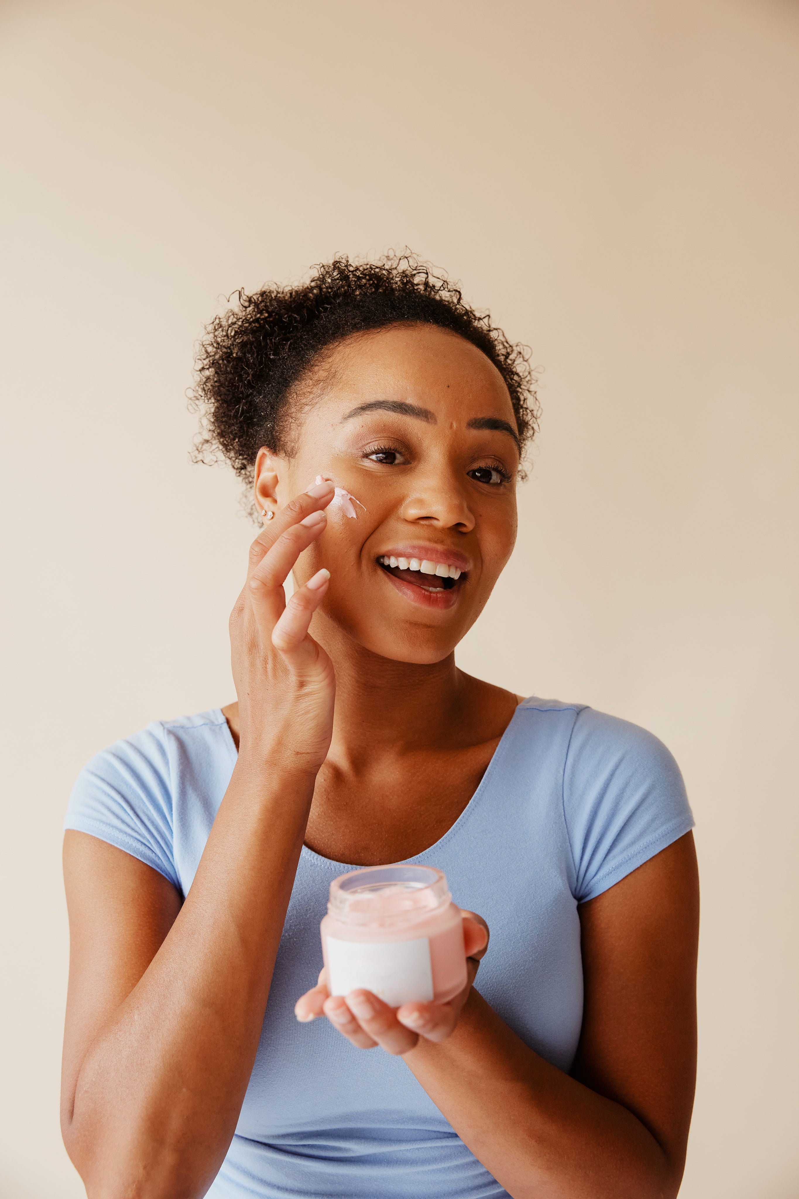 Woman applying goat milk lotion to face