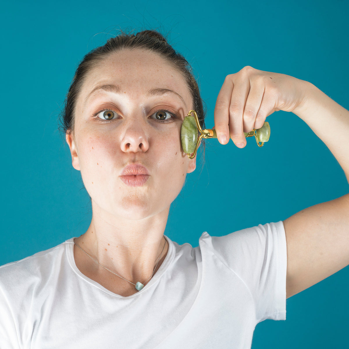 Woman using a jade face roller on her cheekbones